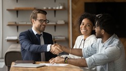 Close up smiling manager and African American family shaking hands, making successful investment or insurance deal, overjoyed young couple and realtor broker handshaking, taking loan or mortgage