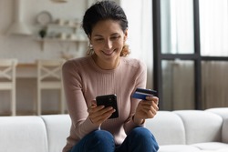Safe mobile banking. Smiling latina lady client hold mobile phone credit bank card do online shopping provide internet payment. Happy young woman enjoy easy fast secure transferring money in ebank app