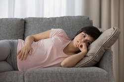 Upset thoughtful pregnant woman lying on couch alone, touching belly, worried frustrated future young mother feeling depressed, sad single mom, divorce or break up, health problem in pregnancy