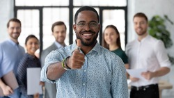 Portrait of happy African American male business leader making thumb up like gesture at camera. Employee satisfied with job and work with great team. Client giving positive feedback to company service