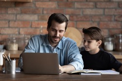Best dad helping schoolboy son, explaining school homework to child. Father and kid using laptop at table together, watching learning webinar, online virtual lesson. Family support, homeschool concept