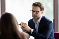 Serious male manager, lawyer, broker, talking to client, giving consultation, advice. Businessman, employer interviewing job candidate for hiring. Business leader in glasses meeting with employee