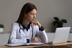 Serious medic professional, doctor, physician using laptop, giving online virtual consultation, making video call to patient, reading electronic medical records. Telemedicine, remote appointment