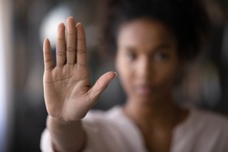 Crop close up focus of African American woman show palm hand against racial gender discrimination. Determined mixed race female make sign gesture protest against domestic violence or abortion.