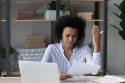 Bad business letter. Distressed worried young african businesswoman read bad news about insolvency bankruptcy in official paper document. Nervous black female employee get debt notification from bank