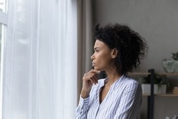 Visualizing perspectives. Serious contemplative black businesswoman young leader look at office window touch chin deep in thoughts solve business problem in mind create new sales strategy. Copy space