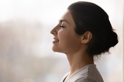 Meditation. Side profile shot of happy serene young indian female face. Calm millennial ethnic lady breath deep with closed eyes meditate feel zen good harmony peace of mind practice yoga meet new day