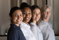 Multi ethnic group of successful confident women office workers professional experts stand in row one after another look at camera. Selective focus on young indian female team leader headshot portrait