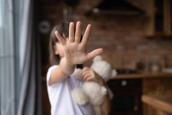 Scared little girl making no sign, showing hand stop gesture at camera. Open palm, outstretched arm close up. Kid standing against domestic violence, abuse, school bullying, Childhood problem concept