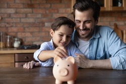 ABC of finance. Smiling father support junior school age son in wish to save pin money teach rational economy wise budget planning. Caring dad hug preteen child boy putting pocket change to piggybank