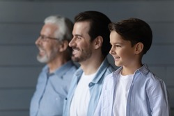 From childhood to retirement. Family dynasty of 3 different age male members stand in line together. Profiles of old age grandpa adult father and small schoolboy son grandchild look forward with smile