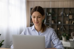 Attractive successful independent 30s woman working on laptop sit in modern homeoffice room. Individual entrepreneur female using modern tech computer do telecommute job, workflow, connection concept