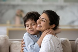 Sincere loving young Indian woman cuddling cute little kid son, showing tender feelings. Happy two generations family enjoying sweet weekend moment together, relaxing at home.