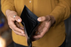 Close up young African American unemployed woman holding opened empty black leather wallet. feeling stressed without cash, having financial problems, suffering from lack of money, bankruptcy concept.
