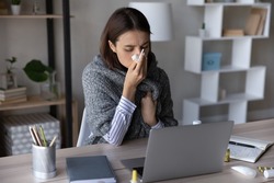 Frustrated sick girl wrapped in scarf suffering from cold, fever, flu, influenza. Ill woman feeling bad, unwell, blowing nose, holding tissue at face. Patient consulting doctor online on video call