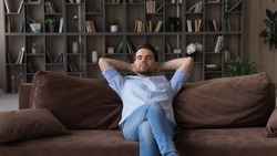 Serene man with closed eyes sitting relaxing on comfortable couch at home alone, enjoying lazy weekend leisure time, daydreaming or taking day nap, dreaming of good future, breathing fresh air