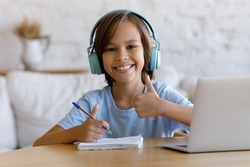 Pre-teen cute boy in headphones enjoy interesting and effective online class with tutor showing thumbs up smile look at camera. Tuition, videocall event, e-study from home, homeschooling, tech concept