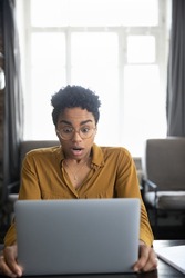 Surprised shocked millennial Black girl looking at computer display with open mouth, gasping. Frustrated laptop user having problems with online work app, software errors, finding mistake