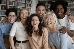 Six happy multi ethnic students laughing pose look at camera standing hugging in college library. Excellent study in university, education in higher institution, multiracial friendship, unity concept