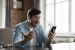 Excited smartphone user man staring at screen in surprise, reading text message getting good news, rejoicing at success, luck, happy opportunity, winning prize, gasping in shock, laughing, smiling