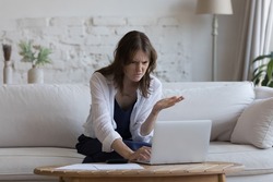 Puzzles young woman analyzing budget at laptop, counting expenses, costs, looking at display with concern, facing problems with payment app, online bank service work, software error