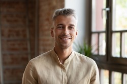 Handsome 30s businessman or employee, head shot. Blond stylish guy posing indoor smiling staring at camera feel optimistic. Professional occupation person, career growth, freelancer portrait concept