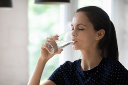 Thirsty dehydrated young woman drinking cold clean water from glass at home, swallowing beverage with closed eyes, recovering hydration balance, keeping healthy habit, lifestyle