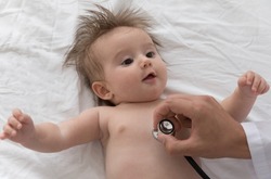 Doctor use stethoscope listens baby heart beat, check breath examining lungs, 0-6 infant lying on white sheets during regular pediatrician visit at home, close up. Healthcare, medical checkup concept