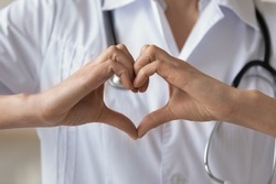 Close up young woman wearing white uniform with stethoscope, doctor showing heart gesture, cardiologist therapist physician gp recommending regular medical checkup, healthcare concept