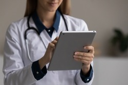 Close up young female general practitioner doctor medical worker holding digital computer tablet in hands, web surfing information or giving distant healthcare advice, modern technology and medicine