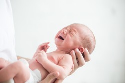 Portrait of a screaming newborn hold at hands, family, healthy birth concept photo, close up