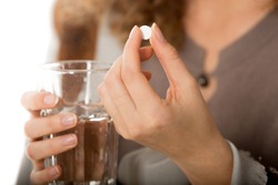Ã�Â¡lose-up view photo of female hands holding one white round pill and glass of water. Young woman taking medication, feeling ill. Healthcare concept