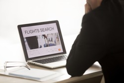 Businessman using laptop for searching cheap low cost business flight, choosing airfare deal, comparing trip prices, booking airplane ticket online on web service, focus on screen, close up back view 