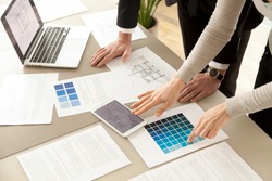 Close up view of Interior designers teamwork with pantone swatch and house building plans on office desk, architects working with blue color palette to choose best paint for home refurbishment