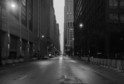 A black and white photo of downtown Chicago. The shot is taken from the middle of the street.