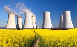 Panoramic view of Nuclear power plant Jaslovske Bohunice with golden flowering field of rapeseed, canola or colza - Slovakia - two possibility for production of electric energy