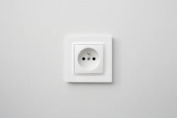 Brand new electrical socket isolated on gray wall. Renovated studio apartment power supply background. Empty copy space white plastic power outlet.