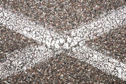 White paint lines in X shape. Lines crossing on grunge asphalt structure. Closeup granular noise background. Street grain pattern. Cracked paint stipe. Marked parking lot point texture.