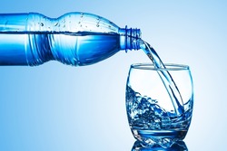 Mineral water background. Pouring water into glass. Plastic bottle drinking water.