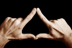 Triangle shape made with fingers. Two hands connected together background. Illuminati triangle. Fingers sign isolated on black.