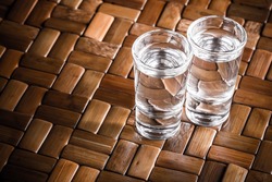 Vodka shots filled with alcohol on wooden bar.
