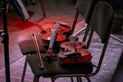 The image of two violins and skirmishes lies on a chair in the theater