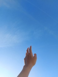 a back hand with beautiful clear blue sky in the background symbolizes a person that reaching a dream as high as the sky