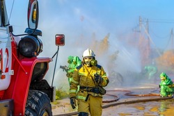 Firefighters in chemical protection suits eliminate an ammonia leak and extinguish a fire at a chemical plant. Rescue operation to create water barriers to toxic chemical cloud after the accident. 