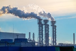 The pipes of the a chemical plant, from which thick white smoke rises into the blue clear sky. Air pollution! Exhaust gases, ozone depletion, greenhouse effect. Industrial landscape of Cherepovets.