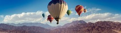 Panorama with colored hot air balloons above mountain peaks for your billboard or web header of travel concept.