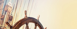 Steering wheel and marine ropes on the old ship for your concept of marine voyage under sails. Nautical equipment on ancient sailing vessel with a wooden wheel of captain.