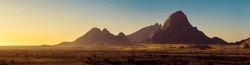 Wide panorama of a stone desert at sunrise in haze  of soft sunlight, mountain landscape of Spitzkoppe hills, Namibia. Travel to wildlife of Africa, extreme tour, adventures to wilderness. 