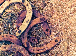 Rusty horseshoes on a straw background - rustic scene in a country style. Old iron Horseshoe - good luck symbol and mascot of well-being in a village house in Western culture.