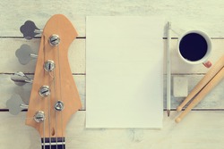 Inspirational musician desktop composing. Electric Bass Guitar, against a white wooden background. Editor's view. Wide copy space for editor's text.